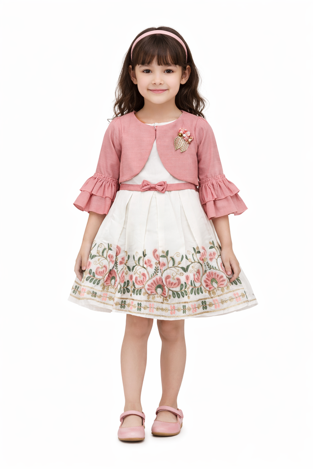 young girl wearing a white muslin party dress with pink floral embroidery and a matching pink ruffled bolero jacket.